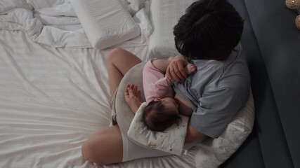 A mother breastfeeds and gently hugs her baby while putting him to sleep in the bedroom