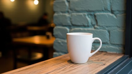 Obraz premium A white mug sits on a wooden ledge with a blurred cafe interior behind