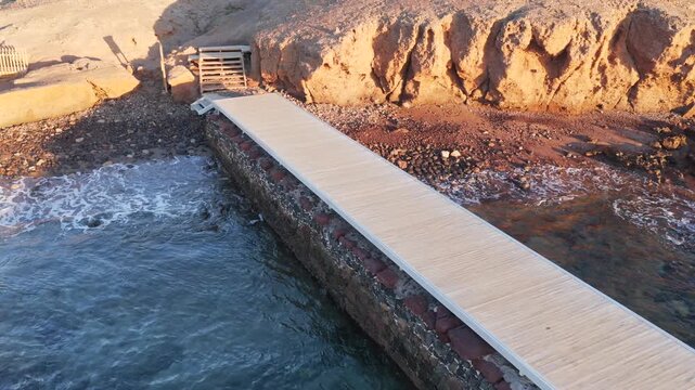 Atlantic Wellness Hub: Cinematic Aerial of the Muelle Viejo Swimming Platform and Tidal Sunbathing Deck on the Volcanic Shoreline of Arinaga, Gran Canaria, Spain