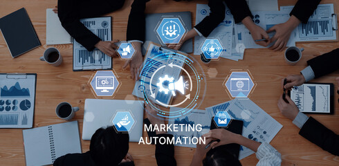 A diverse team collaborates on marketing automation strategies, analyzing data through charts and graphs while using laptops and digital tools on a wooden table. Trope