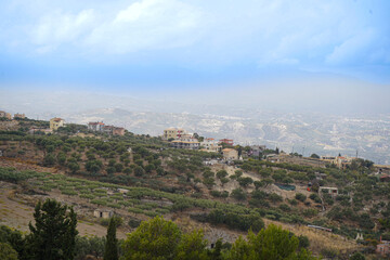 Fototapeta premium Panoramic view of the Archanes valley from the Phourni (Fourni) archaeological site in Crete. Features ancient olive groves and vineyards stretching toward the sea under a moody sky.