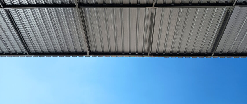 Metal sheet roof curve on blue sky. Modern construction, Metal ribbed arch span roof covering, Large building roof. not ai