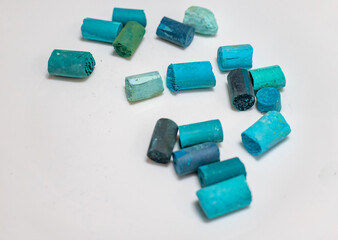 Colored dry pastel set on a white background. Turquoise pastel pieces isolated on a gray background.
