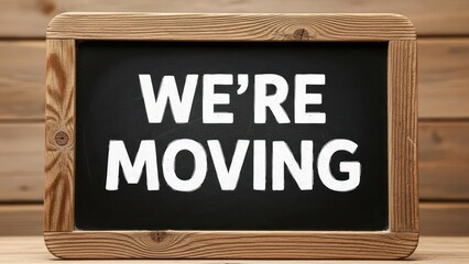 Rustic wooden framed chalkboard announces "We're Moving" in bold white letters