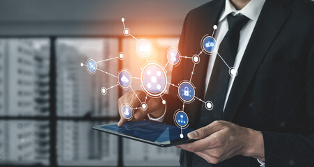 A businessman in a suit engages with a tablet, showcasing digital connections and technology icons in a modern office setting, symbolizing innovation and communication. Tessel