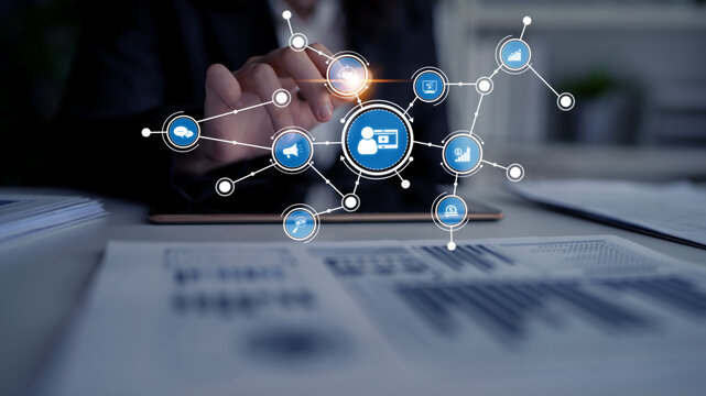 A businessman taps on a touchscreen interface surrounded by digital network icons, symbolizing data analysis and connectivity in a modern workspace environment. Tessel - Powered by Adobe