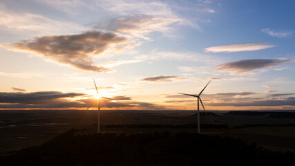 Wind Turbines Silhouetted at Sunrise Over Vast Rural Fields