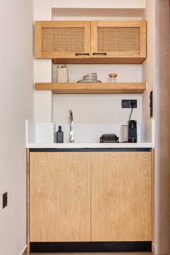 Stylish hospitality corner with custom joinery including upper and lower wooden cabinets a white countertop and coffee making facilities providing a cozy and practical amenities space indoors