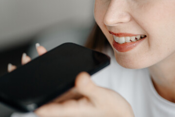 young beautiful caucasian brunette woman recording voice message, smiling widely, casual clothes, white T-shirt, talking by smartphone