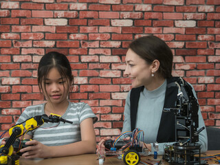 Teacher and student two person diverse individuals collaborating on robotics project in modern workspace. assembling and programming robotic arms, showcasing teamwork, innovation, and STEM education.