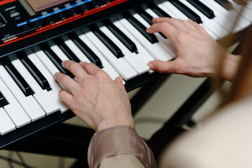 female pianist hands on black and white piano keyboard, close-up view, young woman playing piano, professional musician