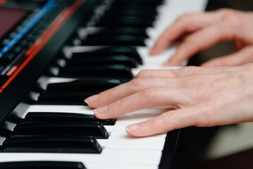 female pianist hands on black and white piano keyboard, close-up view, young woman playing piano, professional musician