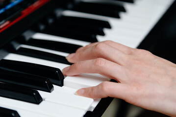 female pianist hands on black and white piano keyboard, close-up view, young woman playing piano, professional musician