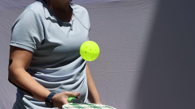 Woman hitting the ball with a green paddle