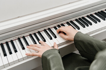 female pianist hands on black and white synthesizer keyboard, close-up view, young woman playing piano, professional musician