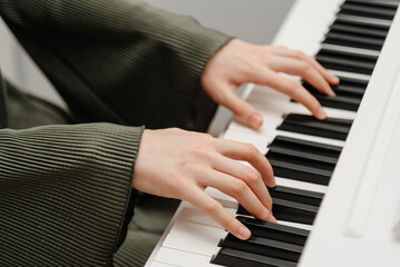female pianist hands on black and white synthesizer keyboard, close-up view, young woman playing piano, professional musician