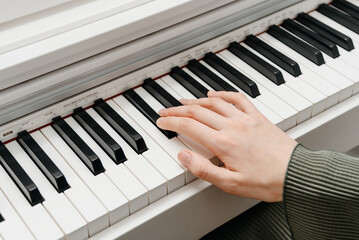 female pianist hands on black and white synthesizer keyboard, close-up view, young woman playing piano, professional musician