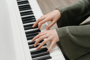 female pianist hands on black and white synthesizer keyboard, close-up view, young woman playing piano, professional musician