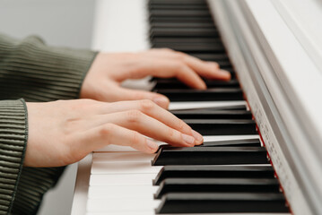female pianist hands on black and white synthesizer keyboard, close-up view, young woman playing piano, professional musician