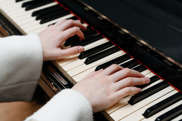 female pianist hands on black and white piano keyboard, close-up view, young woman playing piano, professional musician