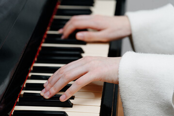 female pianist hands on black and white piano keyboard, close-up view, young woman playing piano, professional musician
