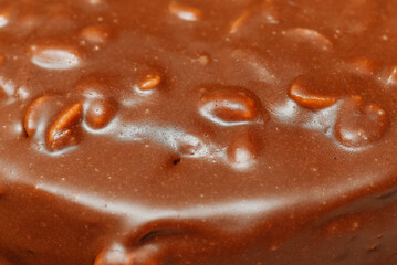 large brown sliced chocolate cake with cream and peanuts, sweet tasty food for holydays and celebrating, selective focus