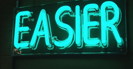 Obraz premium Bright neon sign displays word easier. Dark background emphasizes glowing turquoise lettering. Simple, direct message.
