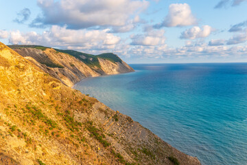 Obraz premium High mountain slopes to the Black Sea coast in Anapa, Russia. Coastline in sunset, beautiful sea scenery. Anapa coast landscape, high cliff