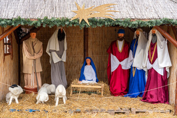 Nativity scene with figures of Mary, Joseph, and others in a stable setting during the holiday season