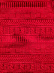 Bright red knitted sweater texture with various geometric patterns, holiday wool background