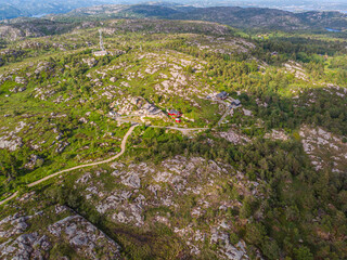 Aerial view of rocky green landscape with scattered rural homes.