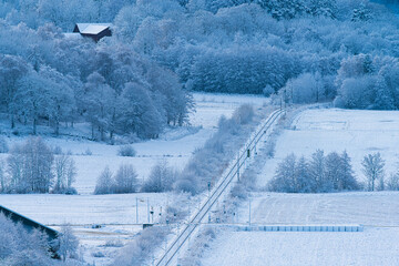 Snowy rural railway line through frozen winter landscape.