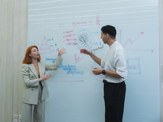 team meeting in modern office where male present stand clap while team member seat around table join. whiteboard background display triangle diagram bar chart emphasizing collaboration professional