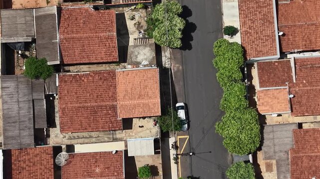 Aerial video footage of a suburban neighborhood with red tiled roofs and trees