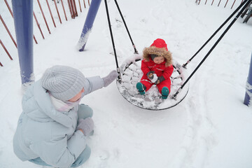 Child Enjoying Snowy Swing in Winter Playground