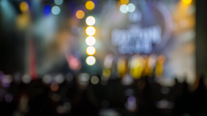 Defocused live stage performance captures dancers in motion with vibrant bokeh lights, colorful spotlights, and audience silhouettes creating an energetic, atmospheric entertainment scene