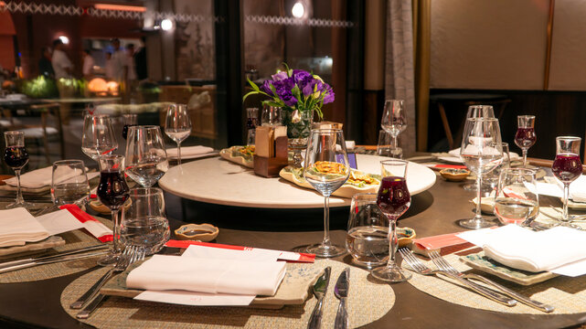 Luxury restaurant round table set for group dining with wine glasses, purple flower centerpiece and Turkish tea creating elegant atmosphere