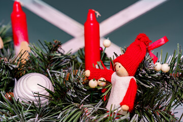 Small figure with red hat among candles and decorations for winter holidays