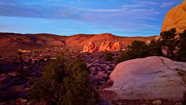 Crimson sunset illuminates valley and rock formations viewed from Ryan Mountain Trail in Joshua Tree National Park California