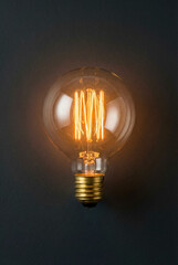 Vintage edison lightbulb glowing orange against dark background