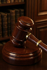 Wooden judge gavel standing on sound block in law library