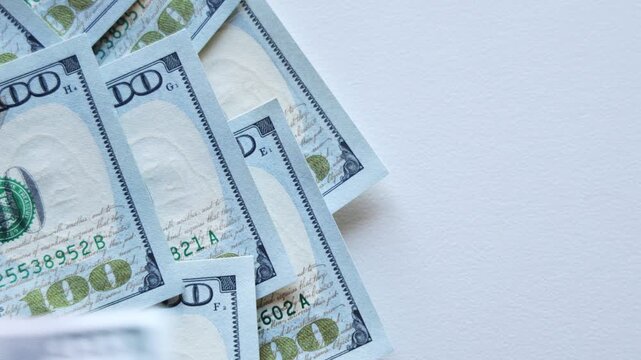 Stacks of hundred-dollar bills are arranged on a clean surface, showcasing the intricate details and textures of the currency in a visually appealing manner