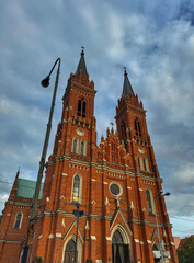 Obraz premium majestic red brick church with two spires against a cloudy sky