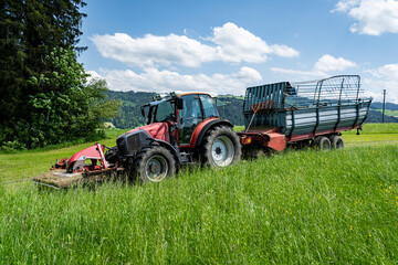 Gr&uuml;nfutterernte im Allg&auml;u, Traktor mit vorgebautem M&auml;hwerk und Ladewagen bei der Grasernte.