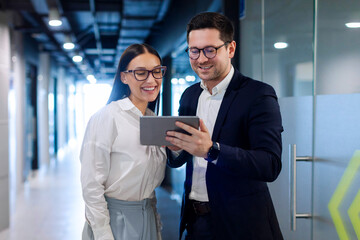 Business professionals interacting in office environment, engaging with digital tablet, discussing...