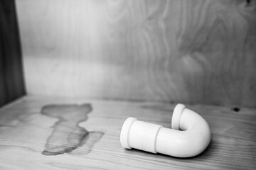 Curved plumbing pipe resting on a wooden surface in a well-lit room during the daytime