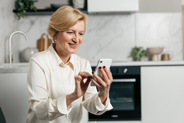 Elderly woman using smartphone at home for communication and information browsing