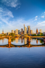 Fototapeta premium The skyline of Frankfurt am Main, Germany, with river and bridges in front during a beautiful summer sunrise