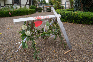 Baumstammsägen auf einer Hochzeit nach der Trauung mit einem weiß lackierten Baumstamm aus Holz...