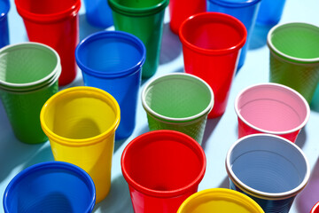Colorful plastic cups on blue background, closeup